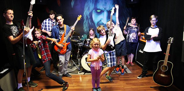 Children performing together with guitars and drums at a Toronto music camp