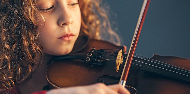 Young girl practising the violin during a private music lesson