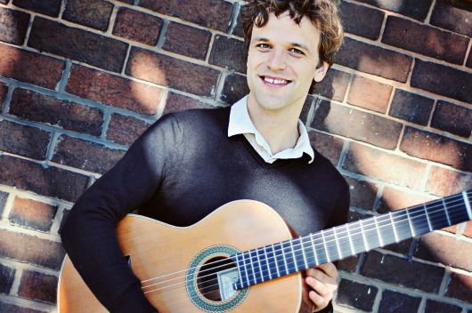 Guitar teacher holding an acoustic guitar during an in-studio guitar lesson in Toronto