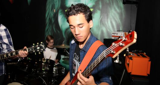 Student playing bass guitar during a band practice at a guitar lesson in Toronto