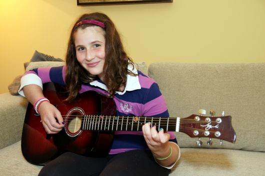 Young student playing acoustic guitar during an online guitar lesson in Toronto