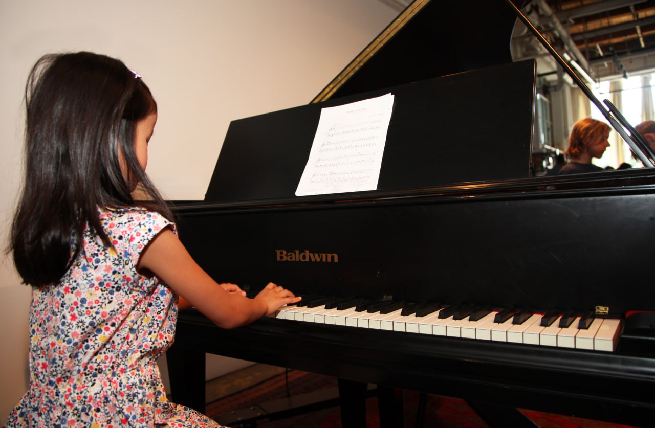 Young student practicing piano on a grand piano during a music lesson