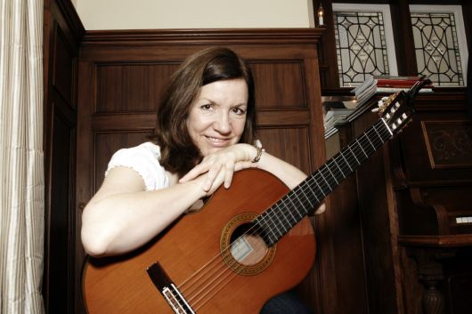Adult student holding a classical guitar during a guitar lesson in Toronto