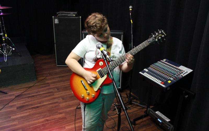 Student playing electric guitar during an in-studio music lesson