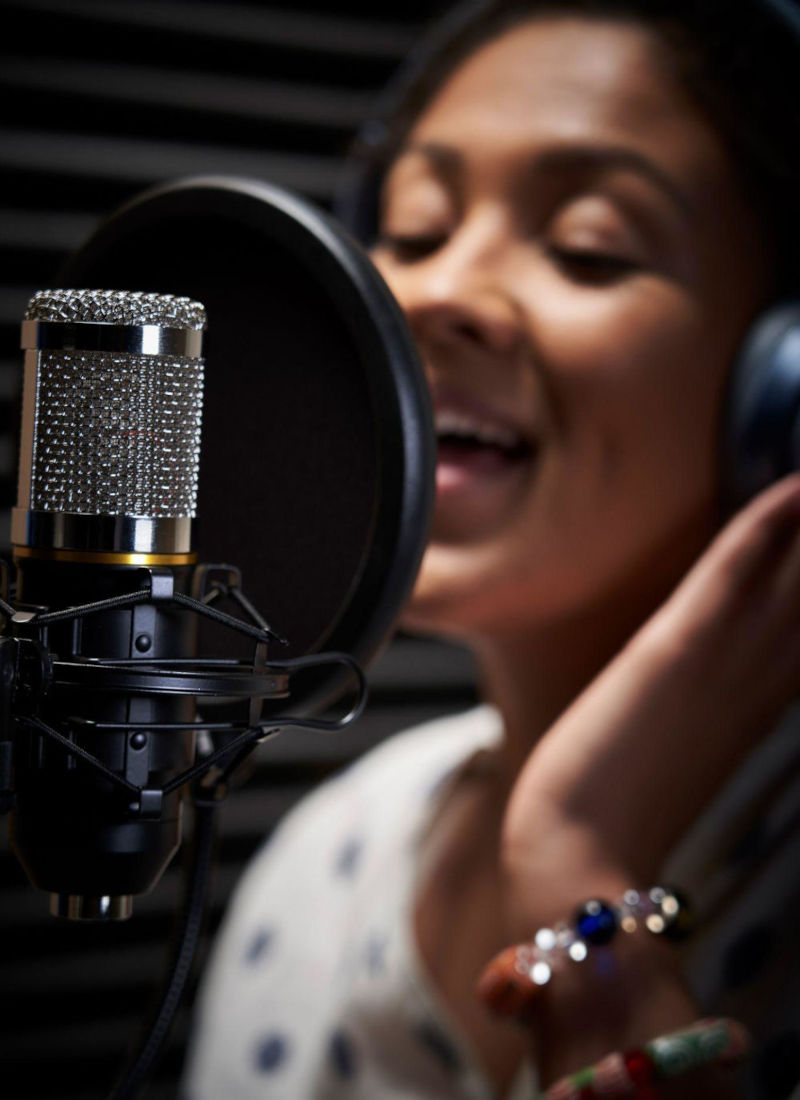 Adult woman singing into a microphone during a singing lesson