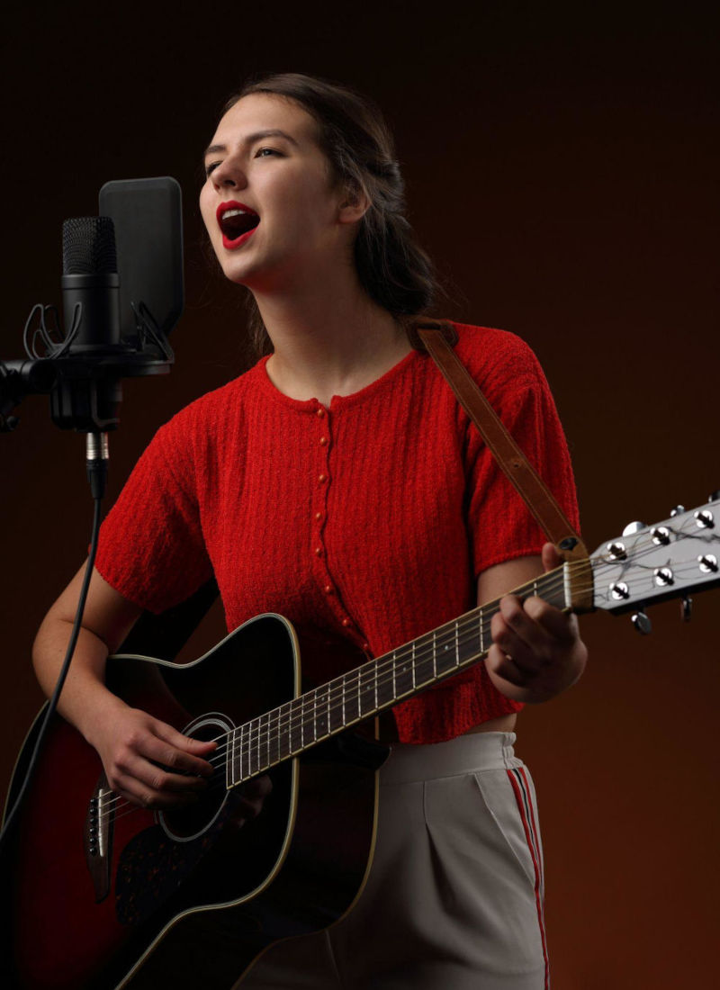 Woman singing and playing acoustic guitar during a vocal lesson